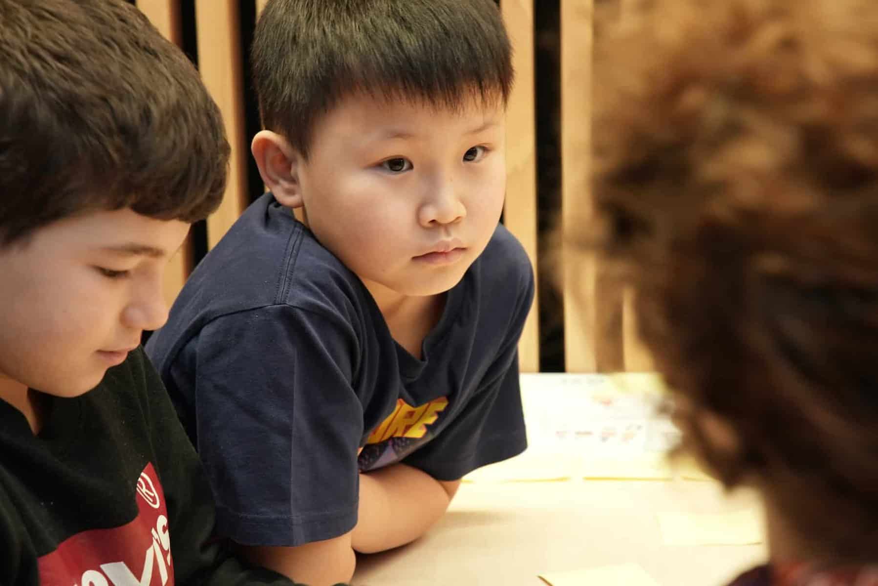 Child leaning against a table during a workshop
